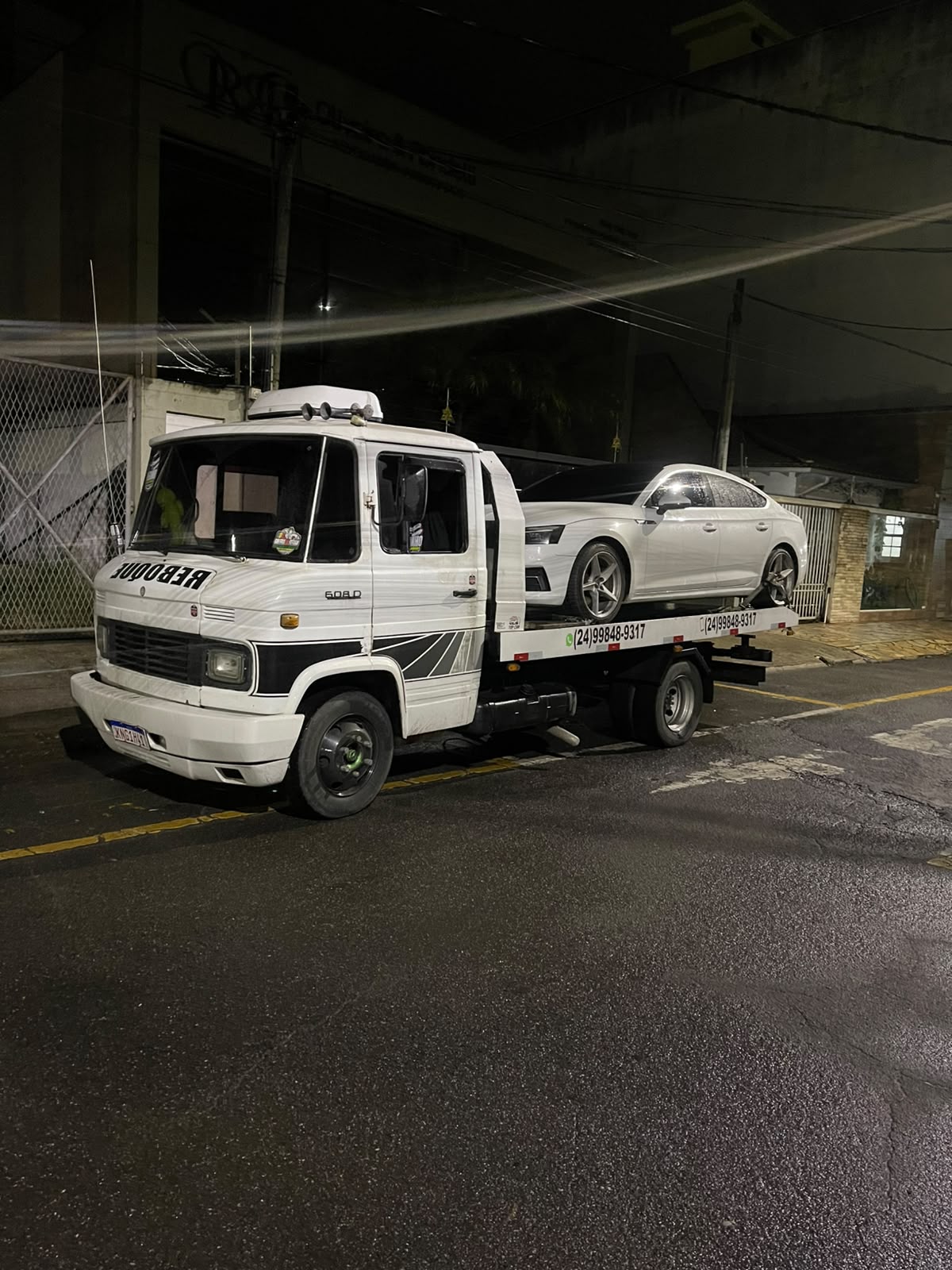 Guincho branco transportando sedan à noite